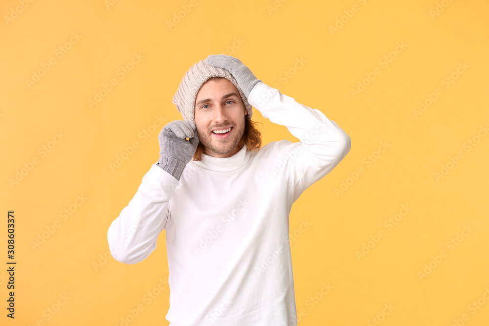 Handsome man in winter clothes on color background