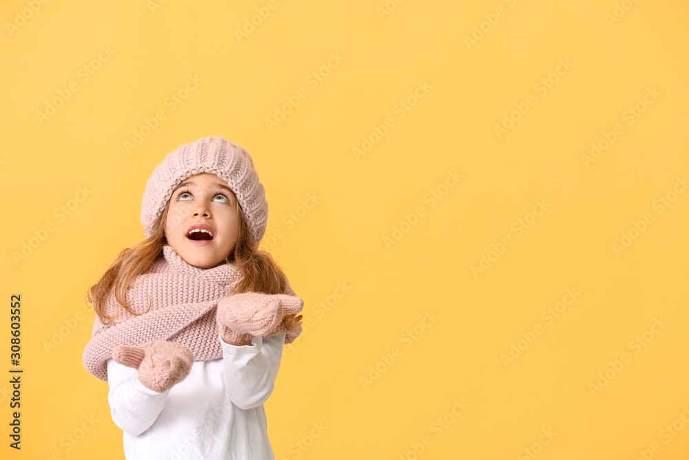 Little girl in winter clothes on color background