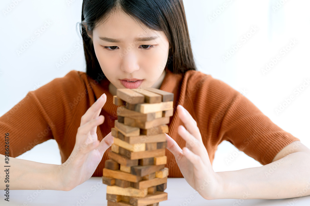 worry stress asian smart woman try to built and protect wooden stack tower risk management strategy 