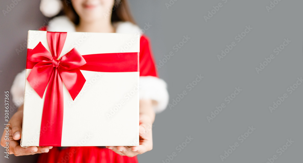 Portrait of young asian caucasian woman girl wearing santa costume and holding gift box on gray back