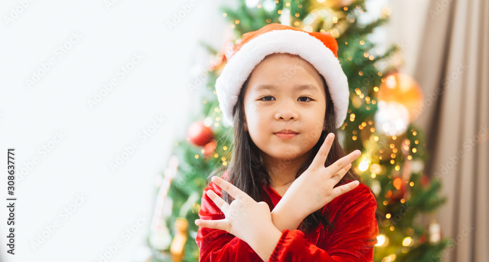 亚洲小女孩微笑着，在圣诞树和白色背景上摆姿势跳舞。小女孩很开心