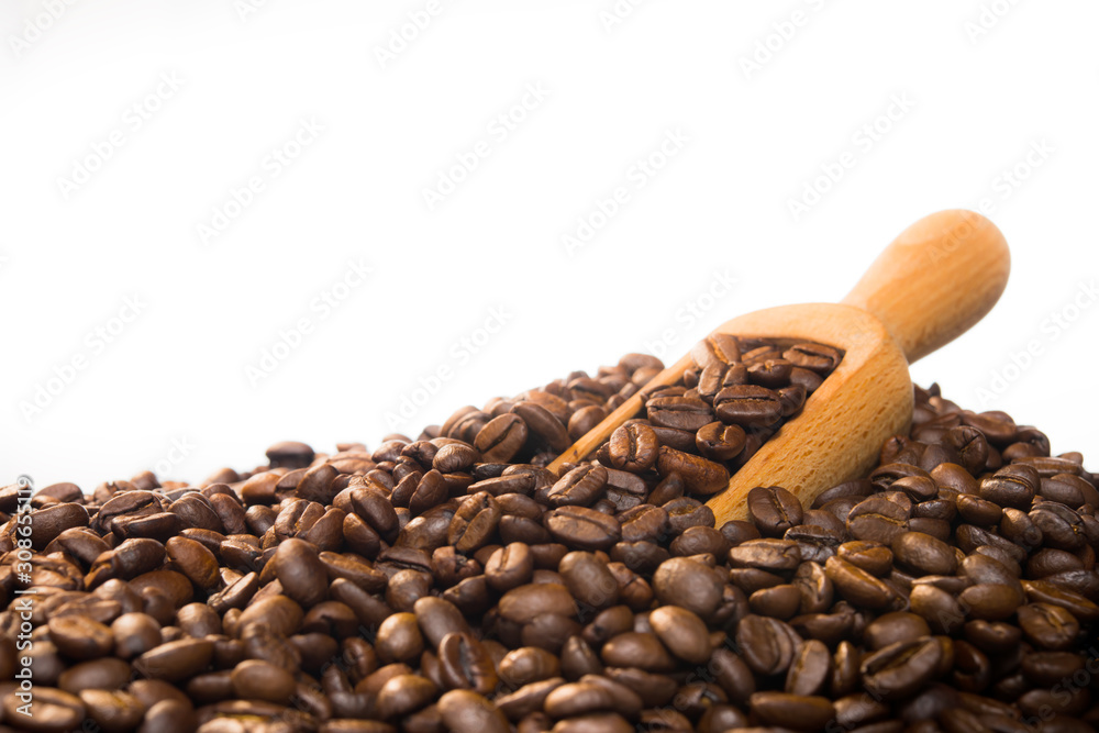 Coffee beans in wooden spoon on pile of coffee beans isolated on white background