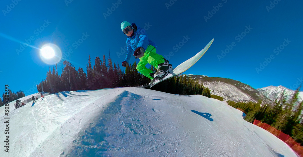 SELFIE: Extreme snowboarder jumps off the roller in the fun park on a sunny day.