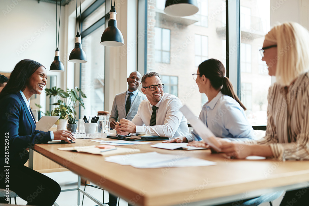 Diverse businesspeople laughing during a meeting around an offic