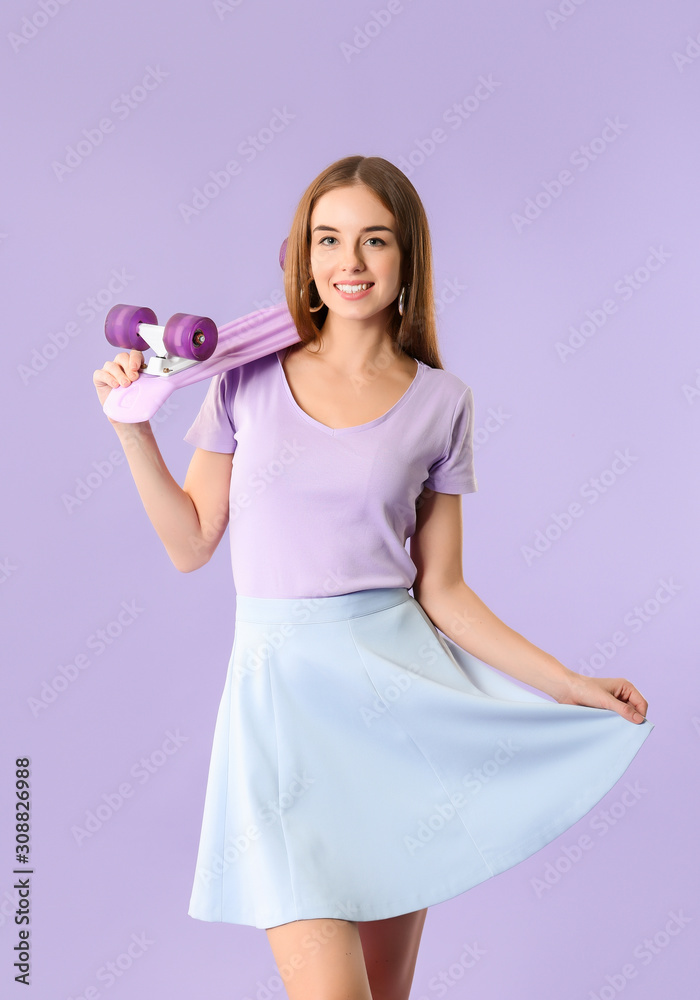 Stylish hipster girl with skateboard on color background