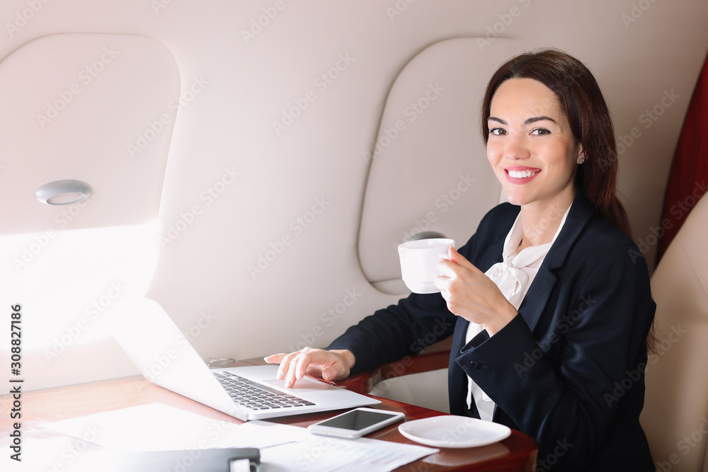 Businesswoman with laptop drinking coffee on board the modern private airplane