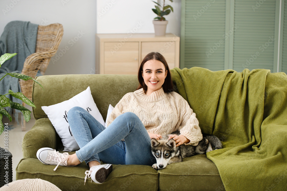 Young woman with funny husky puppy resting at home