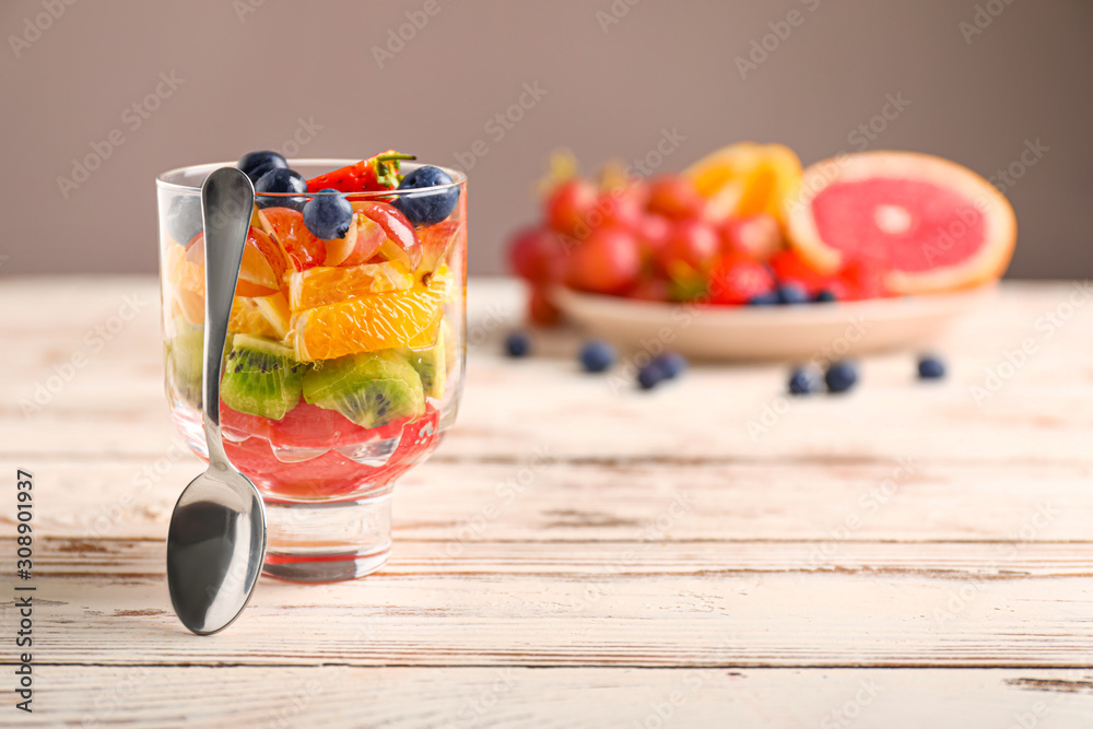 Glass with tasty fruit salad on table