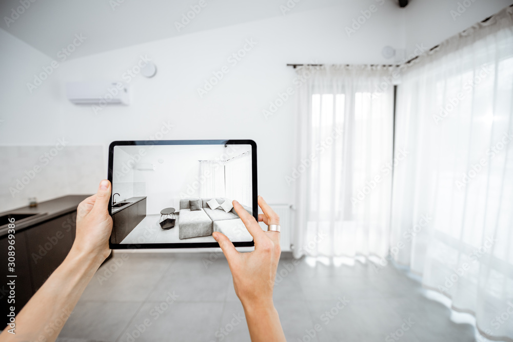 Placing new furniture on a digital tablet into the empty interior, looking how it looks before buyin