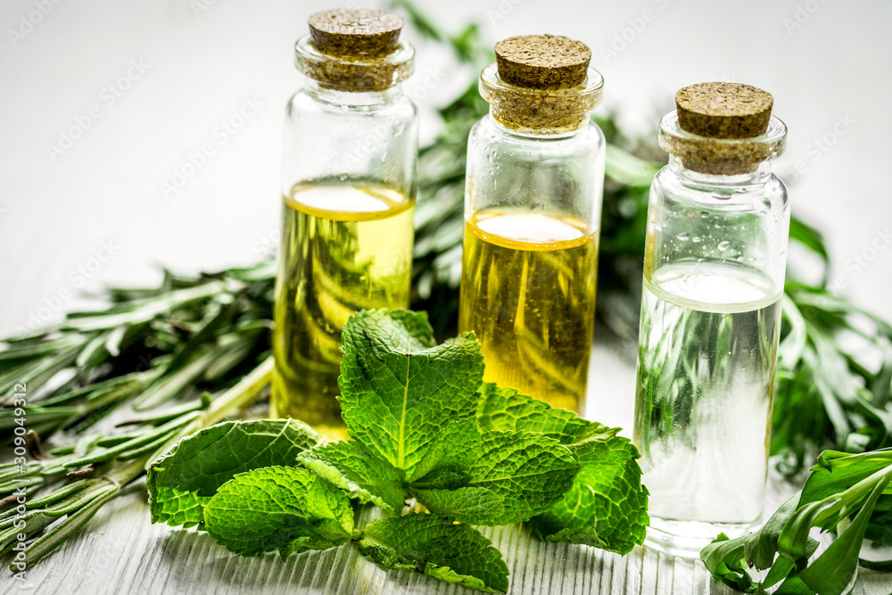 organic oil in bottle with rosemary and mint on light table background