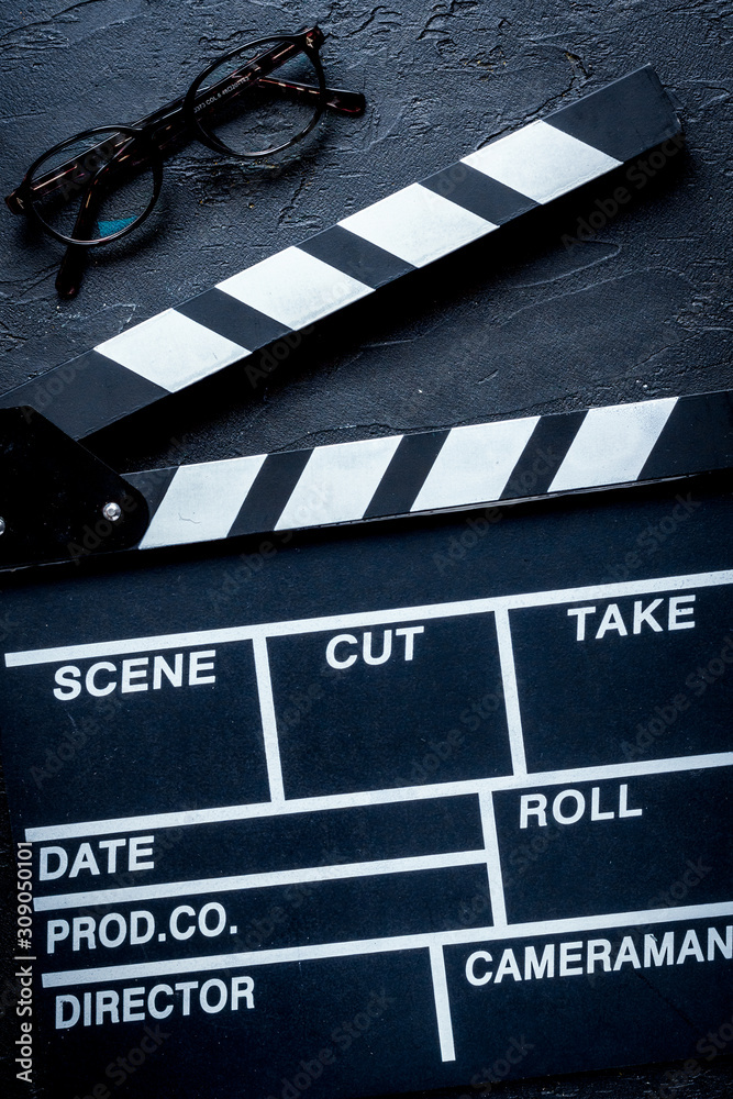 Screenwriter desktop with movie clapper board dark background top view