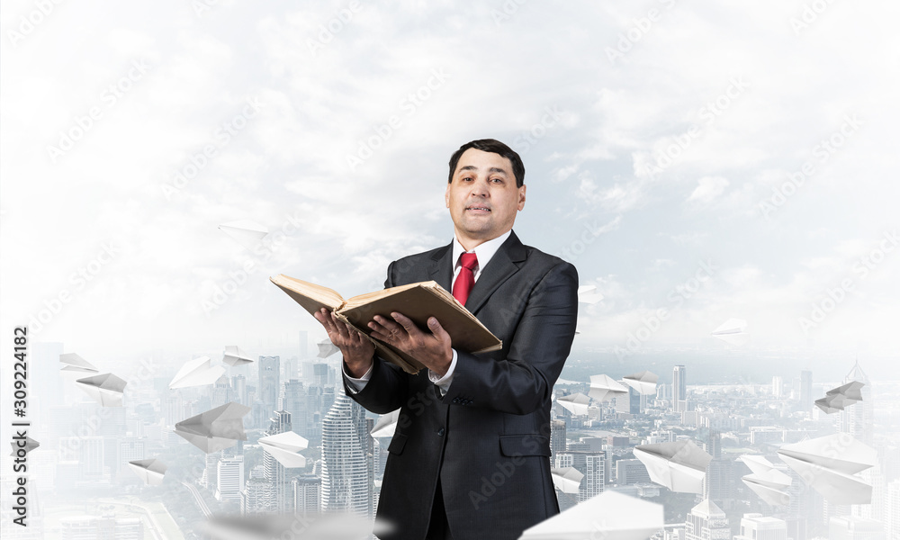 Happy businessman holding open old book