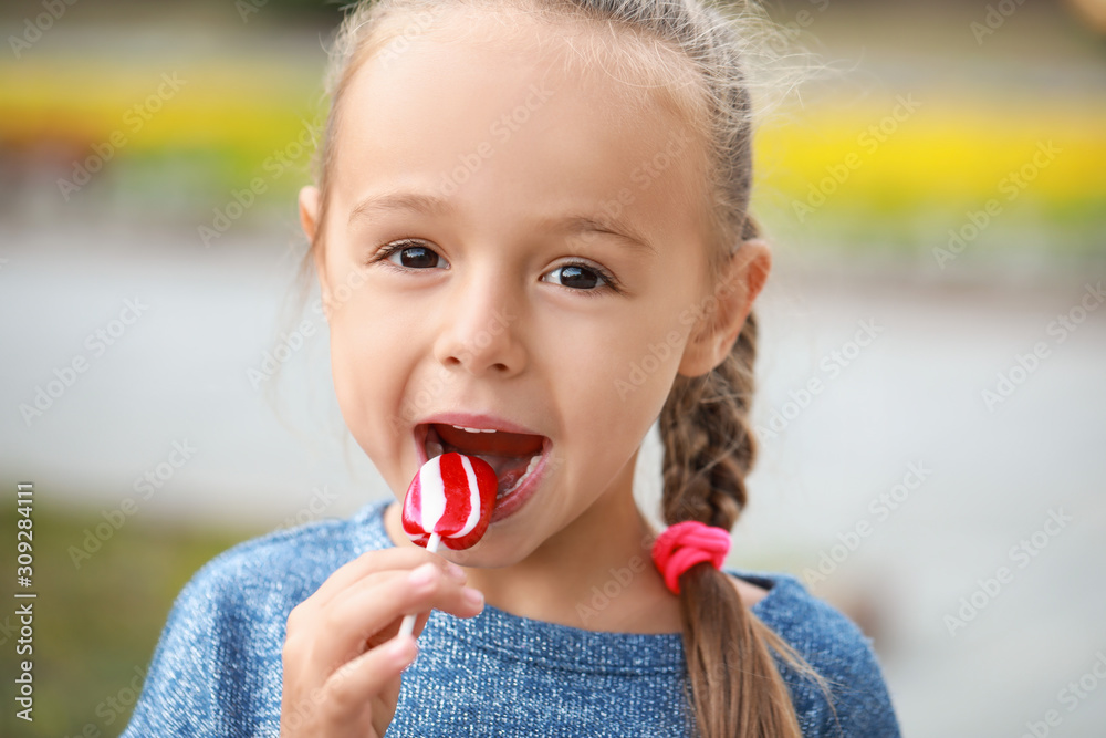 Cute little girl with sweet lollipop outdoors