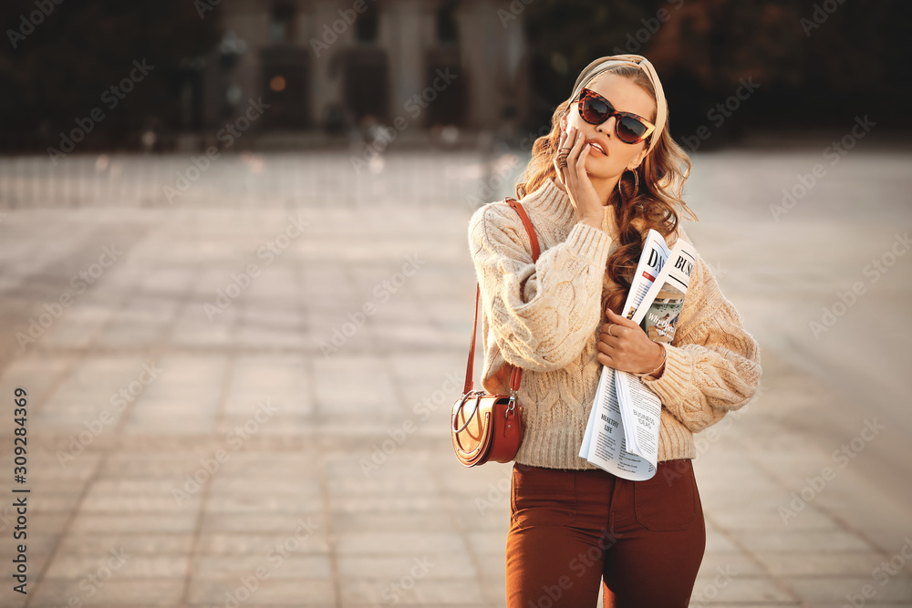 Fashionable young woman with newspaper outdoors