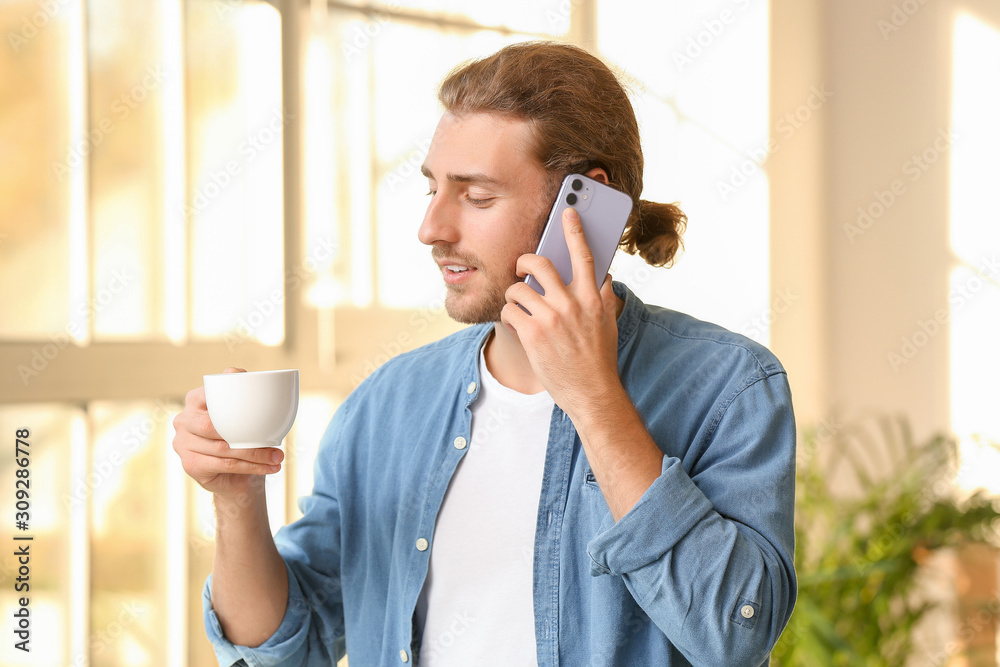 家里拿着一杯咖啡用手机聊天的英俊男人