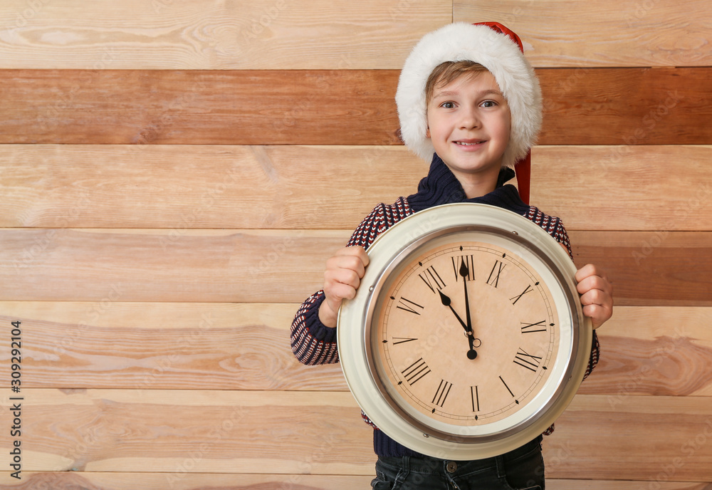 Little boy with clock on wooden background. Christmas countdown concept