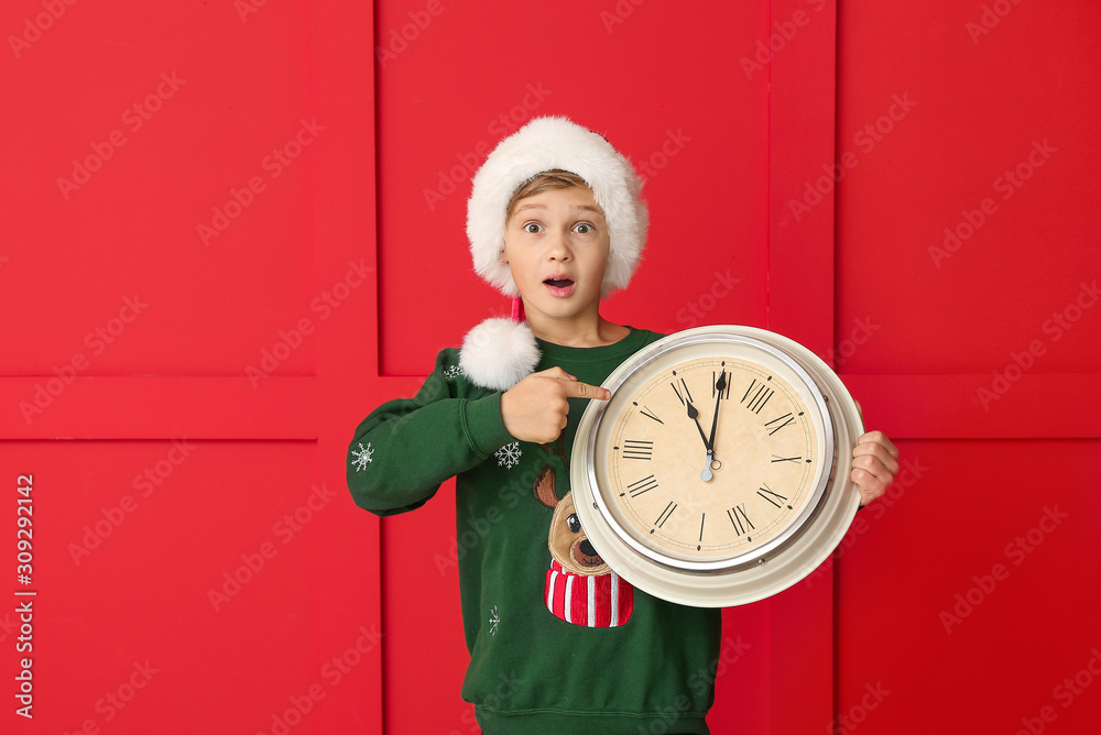 Surprised little boy with clock on color background. Christmas countdown concept