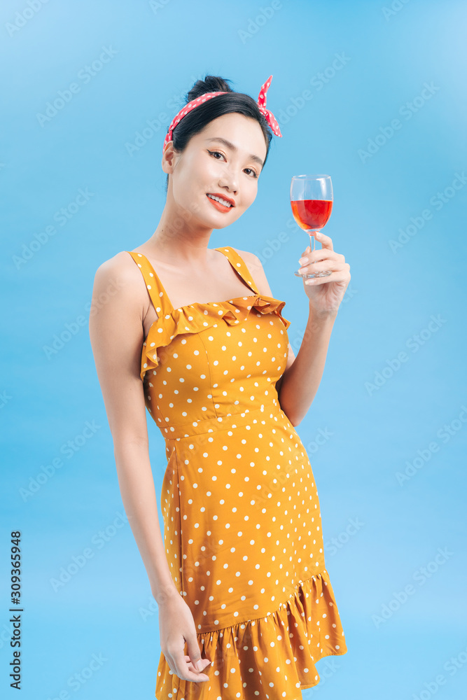 Smiling woman looking at the camera with red wine glass on a blue background