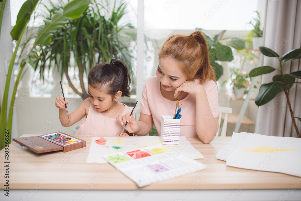 Young Asian beautiful mom with her daughter kid painting at home.