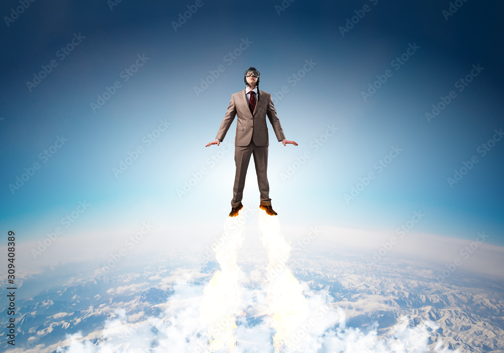 Businessman in suit and aviator hat flying in sky