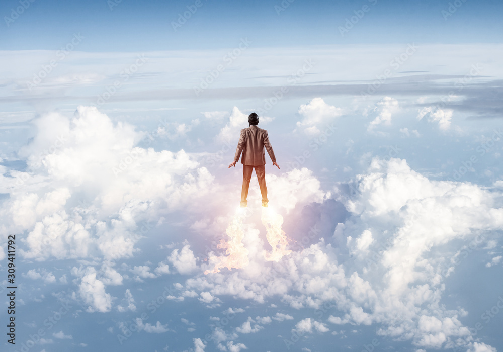 Businessman in suit and aviator hat flying in sky