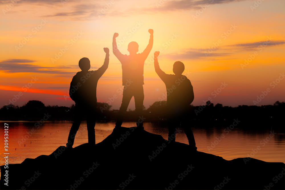 Silhouette of happy teamwork hold hands up as a successful, victory and achieve a business goal in t