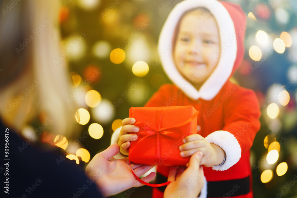 Christmas gift in the hands of a child. Hands of little boy in santa costume with Christmas present.