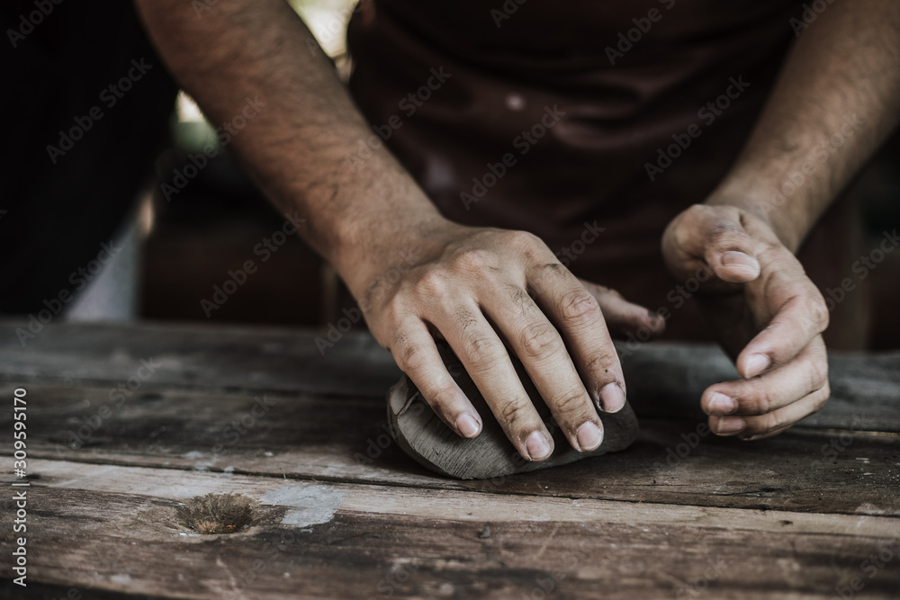 Craftsman hands close up, kneads and moistens the clay before work..