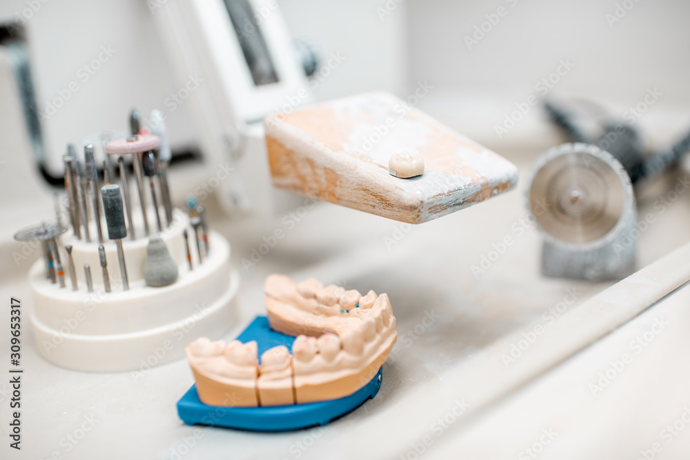 Artificial jaw for implants modeling with set of dental burs at the working place of dental technici