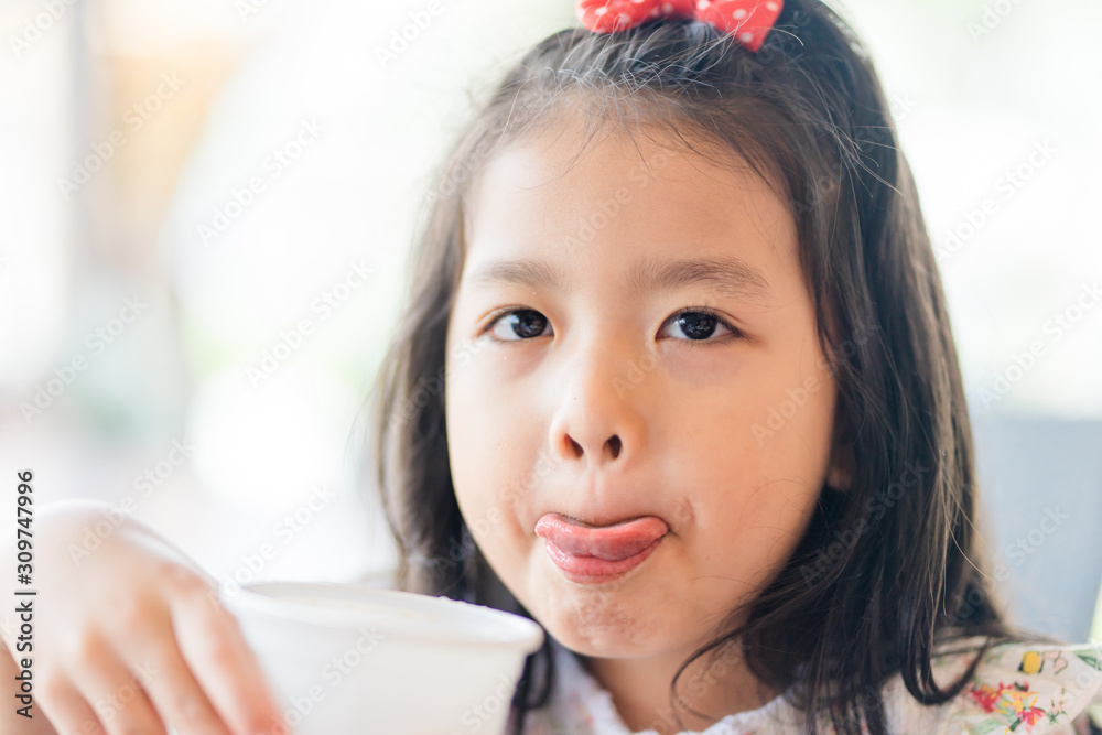 Little asian girl drinking soft drink soda in restaurant.