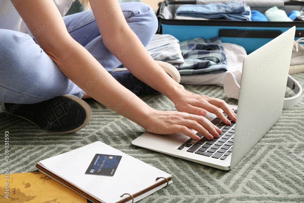 Woman with laptop visiting travel agency website at home