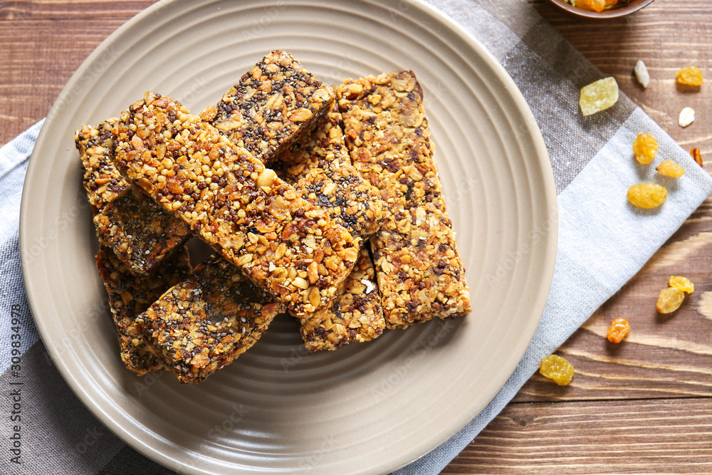 Plate with tasty granola bars on wooden table