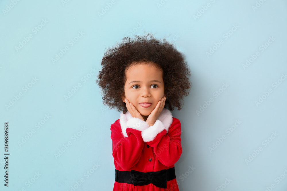 Little African-American girl in Santa costume on color background