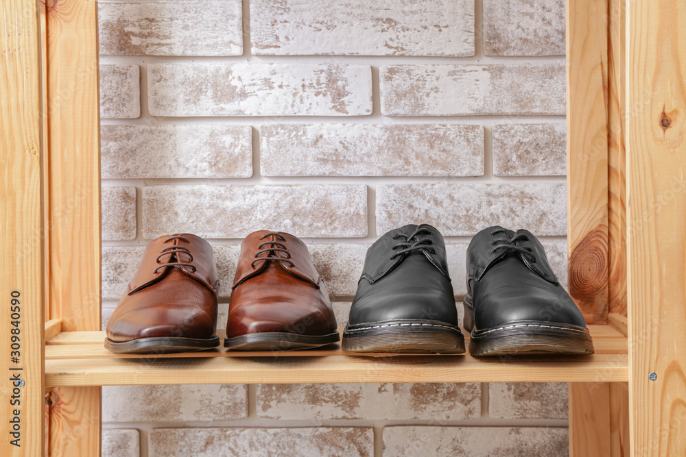 Shelf unit with stylish shoes near brick wall