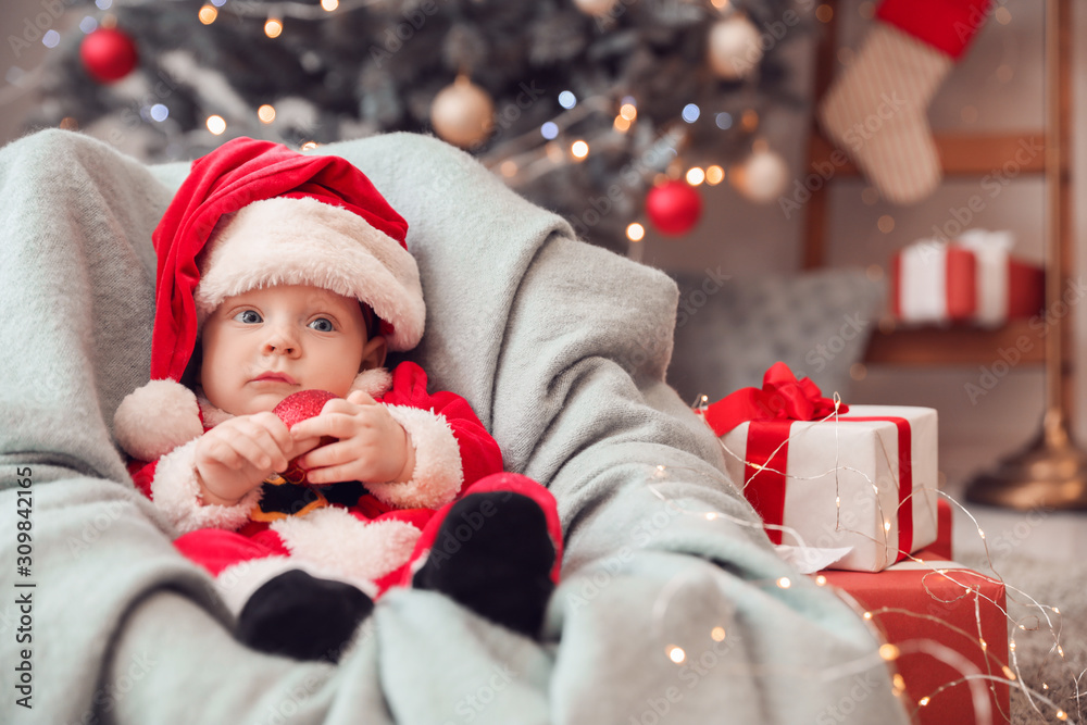 Cute little baby in Santa Claus costume at home