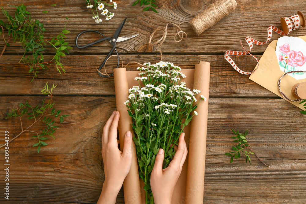 Female florist making beautiful bouquet on wooden background