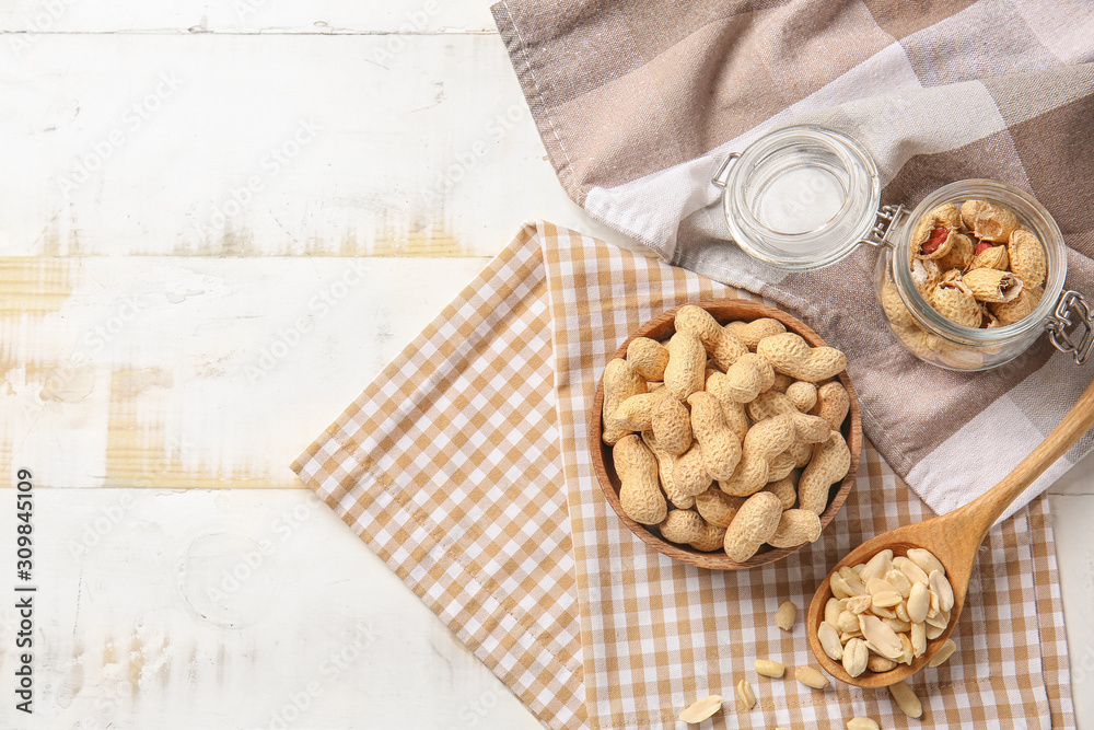 Tasty peanuts on white wooden background