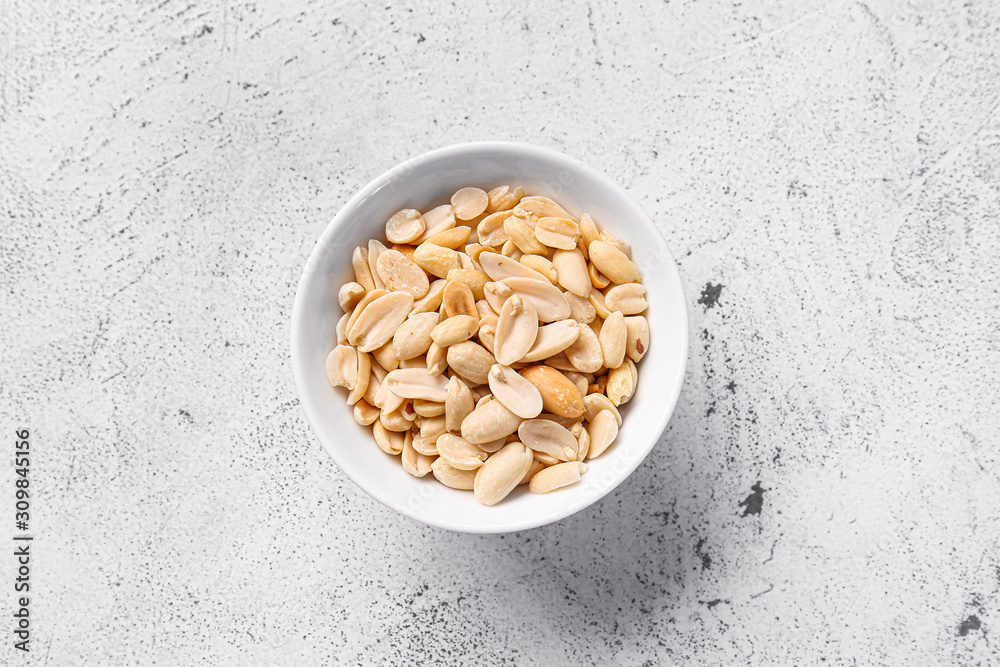 Bowl with peanuts on white background