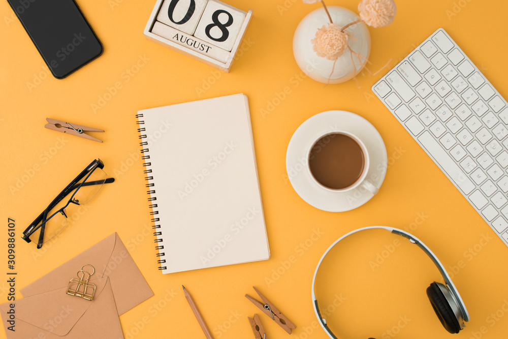 Mordern workplacewith keyboard, headphone, coffee, glassess, phone, pen on orange background. Top vi