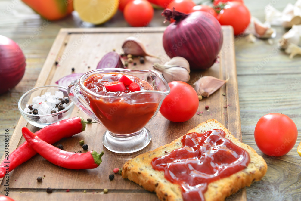 Gravy boat with barbecue sauce, toasted bread and spices on wooden table