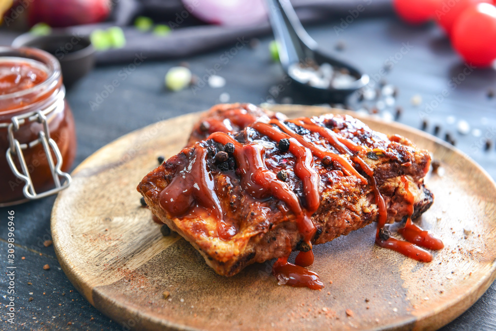 Plate with fried meat and barbecue sauce on dark table