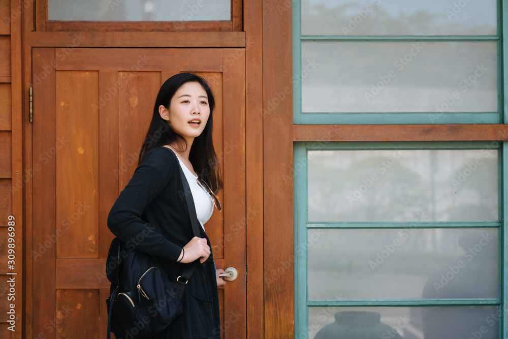 asian young girl in white t shirt with backpack open old wooden door of throne house. charming woman