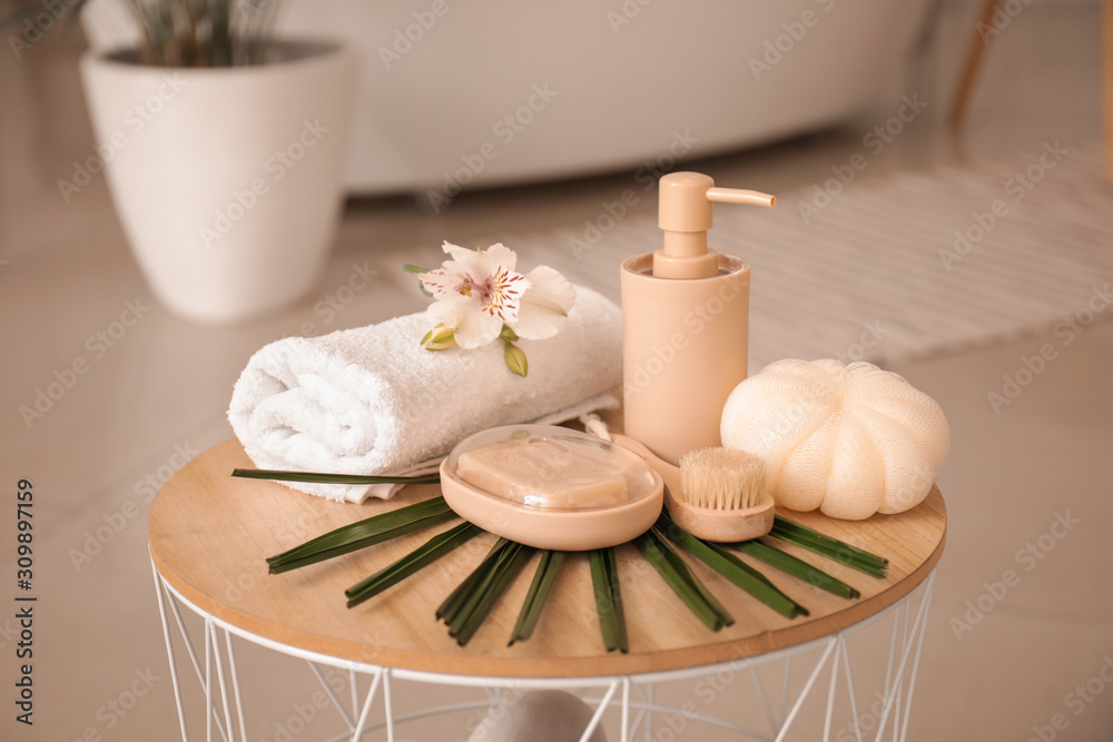 Clean towel with cosmetics and supplies on table in bathroom