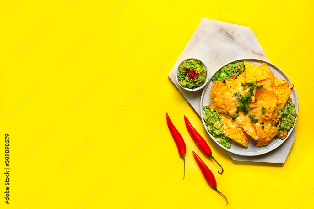 Board with tasty nachos and guacamole on color background