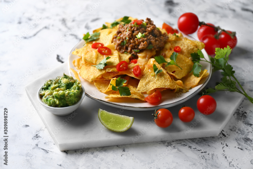 Plate with tasty nachos, meat and guacamole on white background