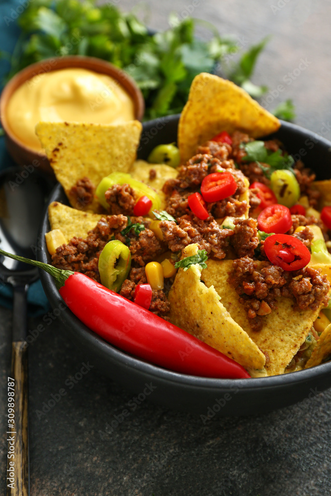 Bowl with tasty chili con carne and nachos on table, closeup