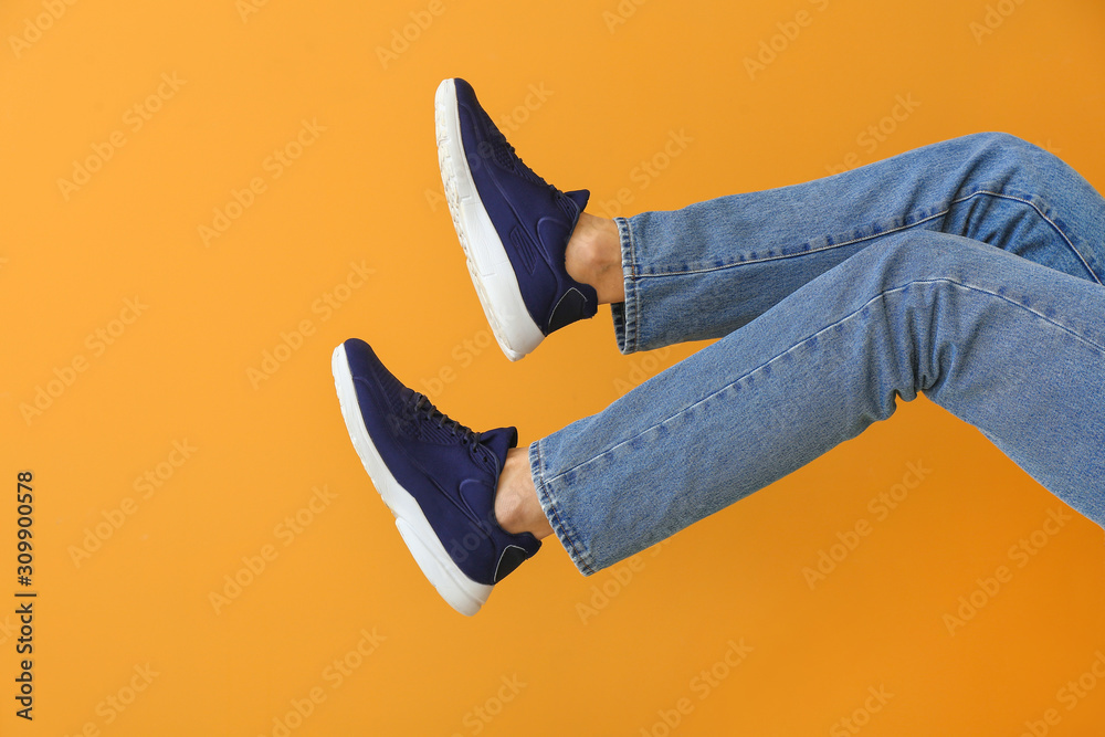 Young man in stylish shoes on color background