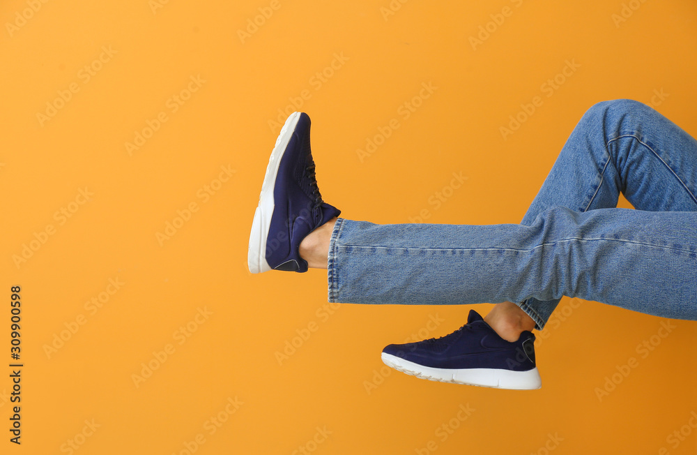 Young man in stylish shoes on color background