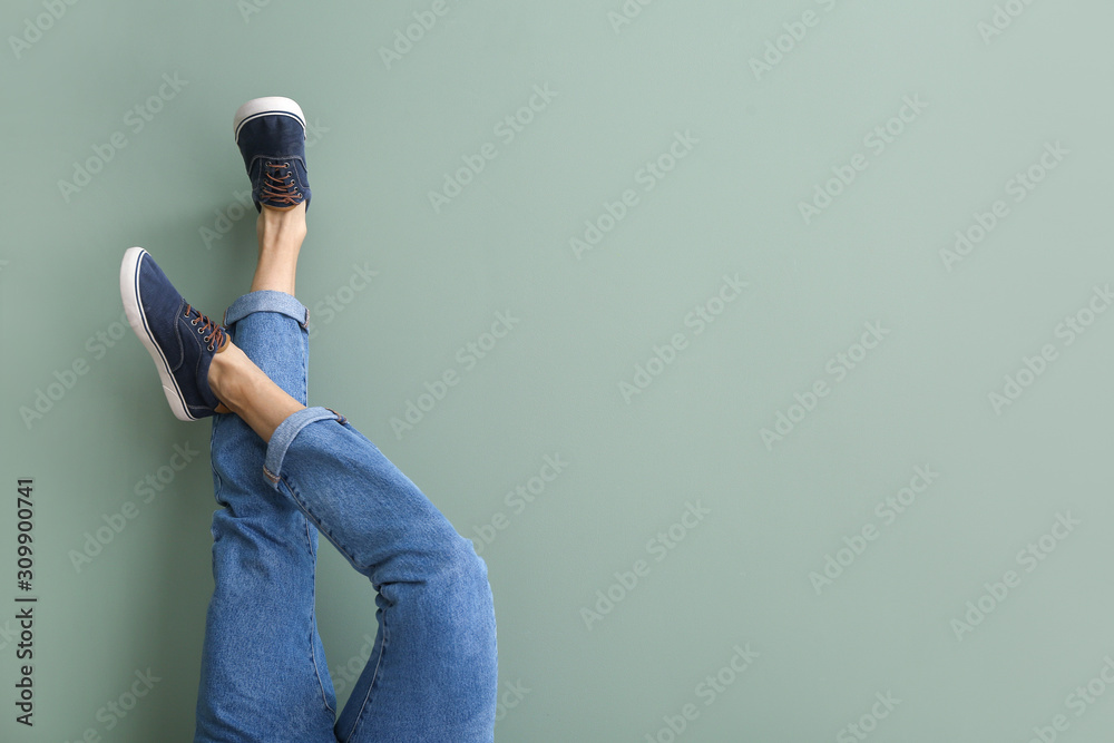 Young man in stylish shoes on color background