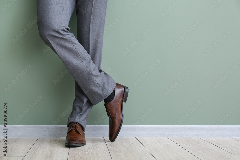 Young man in stylish shoes near color wall